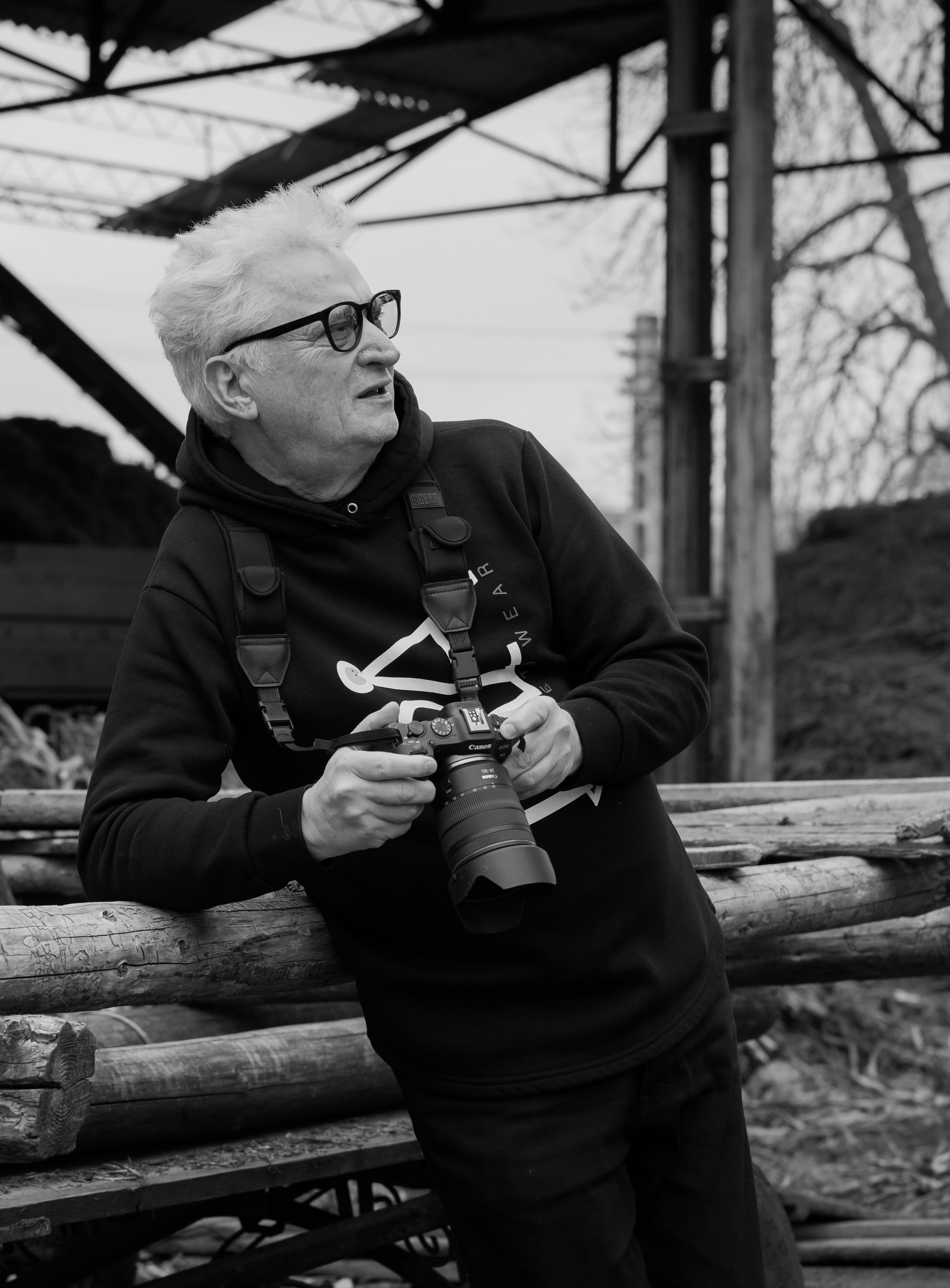 Adam Soch holding a camera, seated outdoors.