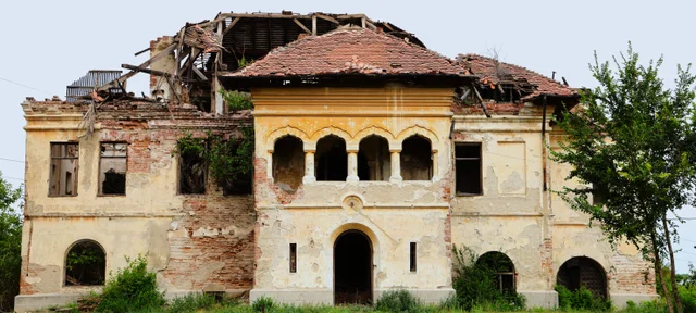 A ruined manor with a collapsed roof and an arched upper loggia.