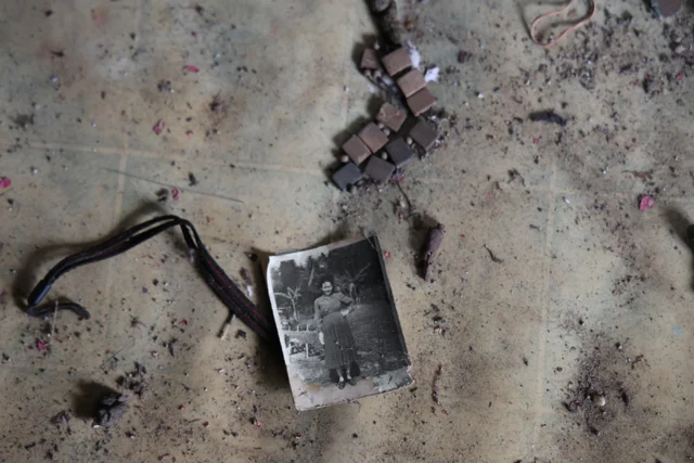A black-and-white photograph lies among rubble on the floor.
