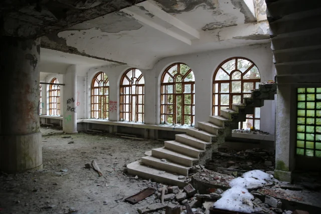 A broken staircase beneath a row of tall arched windows.
