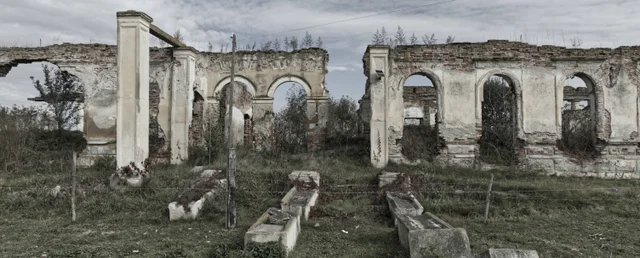 Roofless ruins with arched windows and overgrown walls.